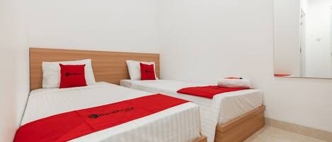 Ein Hotelzimmer mit zwei Einzelbetten, jeweils mit Holz Kopfteil und weißer Bettwäsche.