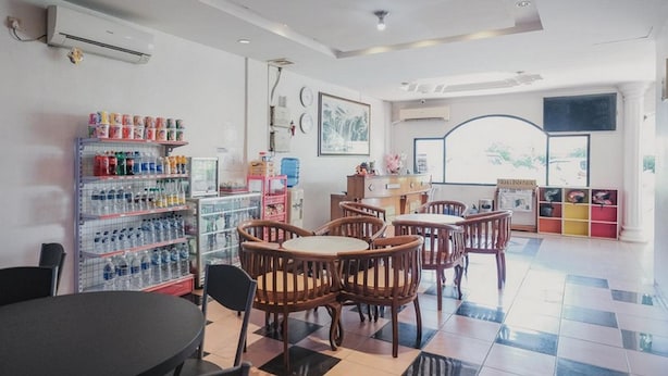 Un restaurant avec des chaises et des tables en bois, un distributeur d’eau et une étagère remplie de bouteilles d’eau.