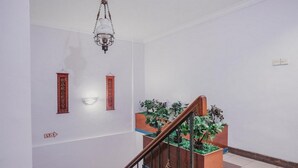 Un escalier avec une rampe en bois, un luminaire suspendu et deux éléments de décoration rouge fixés au mur.