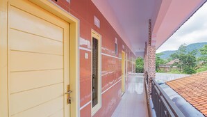 Un pasillo con una puerta amarilla y una pared roja, que lleva a un balcón con techo de tejas.