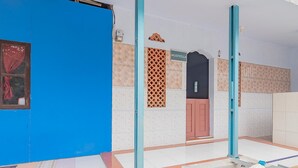 Una habitación con pared azul, piso de baldosas, puerta con un cartel y ventana con cortina.