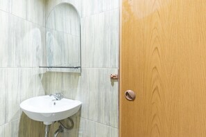 A bathroom with a white sink, a mirror, and a wooden door.