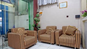 A reception area with striped armchairs, a glass door, and a wall-mounted sign.