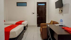 Habitación de hotel con dos camas, un escritorio, una silla, un televisor y una puerta.