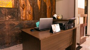 A wooden reception desk with a laptop, a calendar, and a printer.