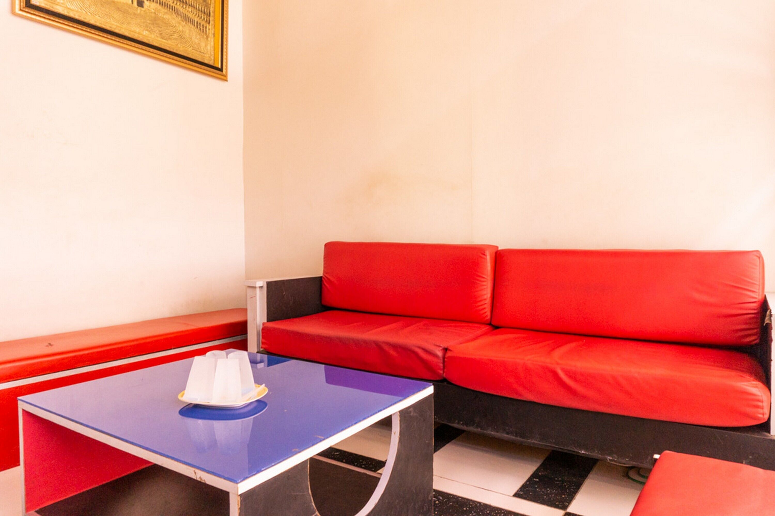 A room with a red sofa, a blue table with a white object on it, and a black and white checkered floor.