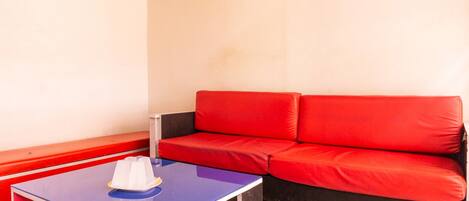 A room with a red sofa, a blue table with a white object on it, and a black and white checkered floor.