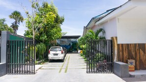 A gated driveway leading to a building with a sign that reads "BAIM HOME STAY."