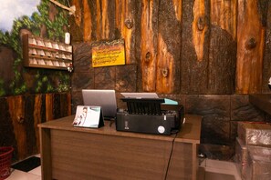 Un comptoir d’accueil en bois, avec un ordinateur portable, une imprimante et un calendrier.