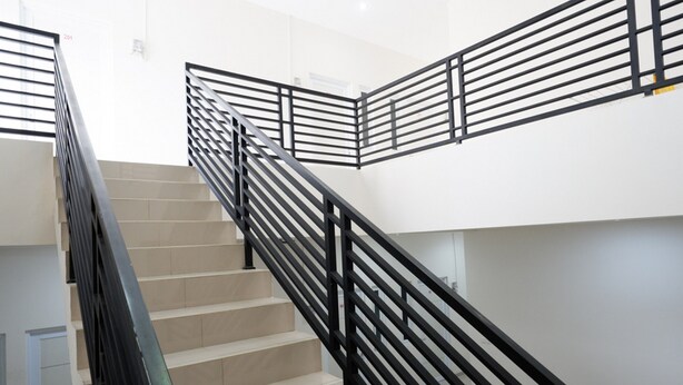 Eine Treppe mit schwarzen Geländern und beigen Stufen.
