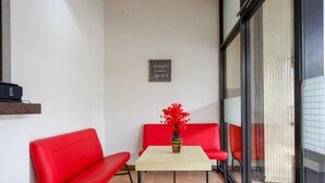 Ein Zimmer mit einem roten Sofa, einem kleinen Tisch mit einer Topfpflanze und einem an der Wand befestigten Schild.