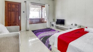 A hotel room with a bed, a sofa, a TV, and a window with curtains. - RedDoorz Plus @ Purwodadi (Lawang)