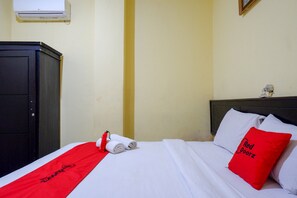 Habitació d'hotel amb llit, tovallola vermella i almoina amb el text "Red Doorz".