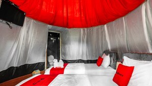 Une chambre d’hôtel avec deux lits, une literie rouge et blanche, et un baldaquin rouge.