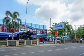 A hotel with a blue facade, palm trees, and a sign that reads "Hotel Indonesia".