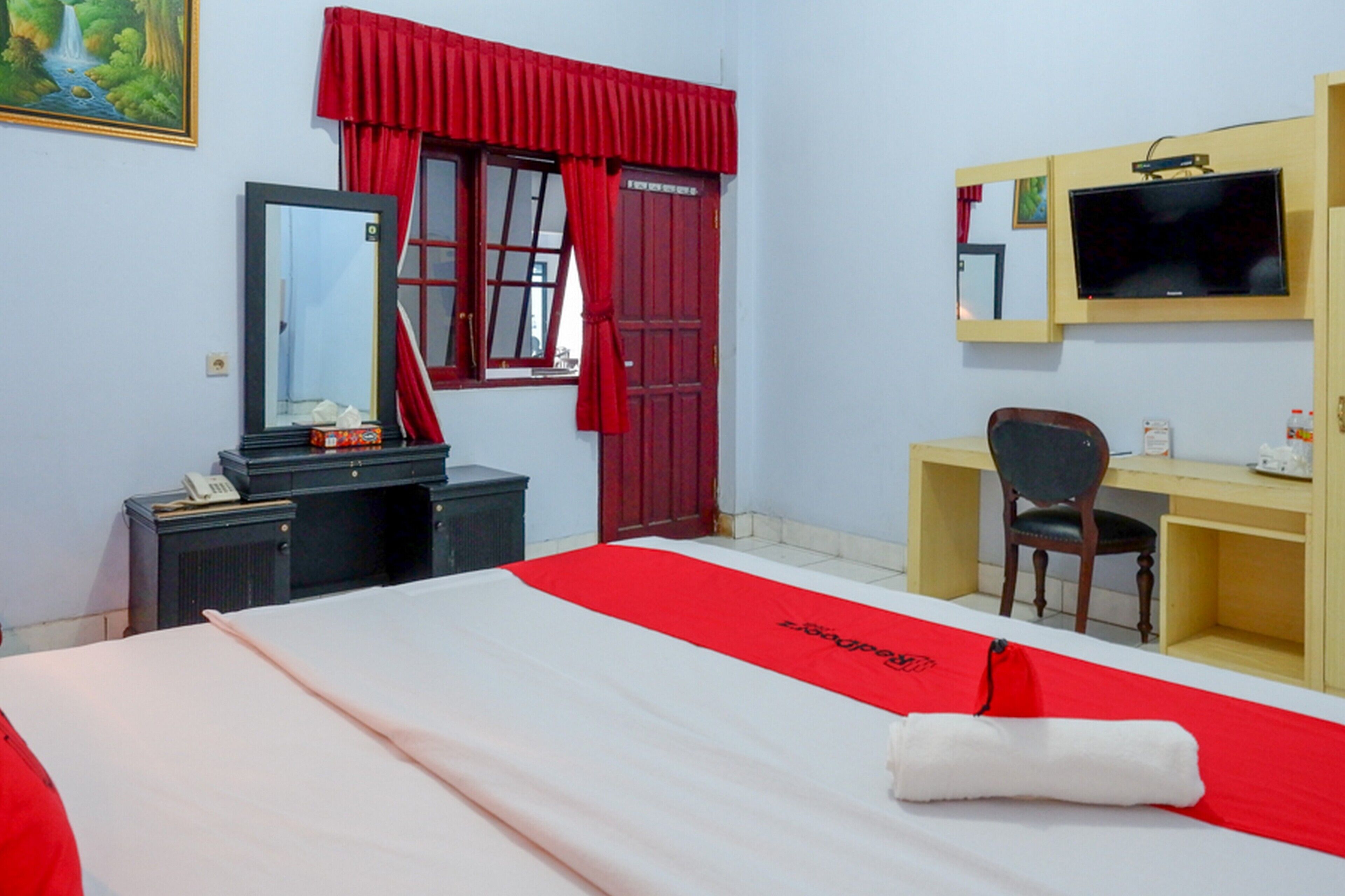 A hotel room with a bed, a desk, a chair, a TV, and a wardrobe.