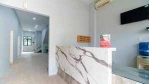 A reception area with a marble counter, a mounted TV, and a water dispenser.