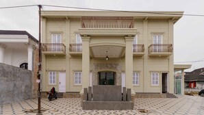 A large, two-story building with a symmetrical facade, a central entrance, and a balcony on the upper floor. - RedDoorz Plus Syariah @ Jalan Dr Sutomo Padang (Padang)