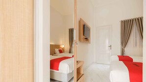A hotel room with two beds, a TV mounted on the wall, and a sliding door. - RedDoorz Plus Syariah @ Jalan Dr Sutomo Padang (Padang)