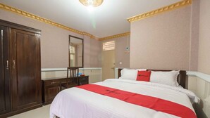 A hotel room with a large bed, a wardrobe, a desk, and a mirror. - RedDoorz Plus Syariah near RSUP Dr. M. Djamil Padang (Padang)