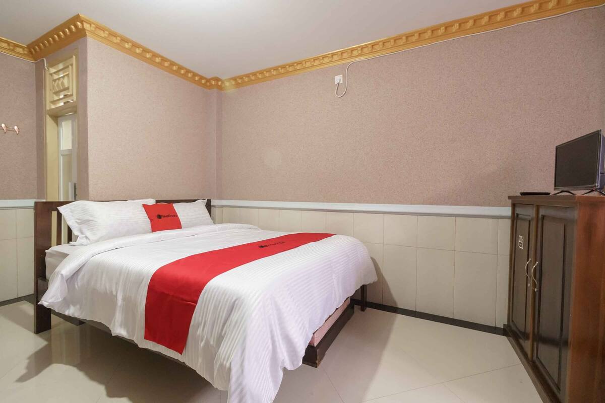 A hotel room with a bed, a television, and a wardrobe.