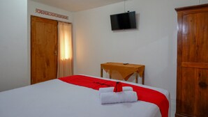 Une chambre d’hôtel avec un lit, une télévision, une armoire en bois et une petite table.