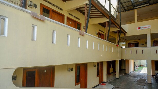 Un intérieur d’hôtel à plusieurs niveaux, avec un couloir central, des portes en bois et une enseigne RedDoorz.