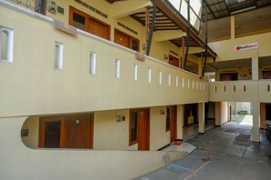 A multi-level hotel interior with a central corridor, wooden doors, and a RedDoorz sign.