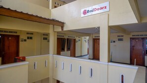 Un couloir d’hôtel avec de nombreuses portes, chacune portant un numéro. Une enseigne RedDoorz est visible au-dessus du couloir.