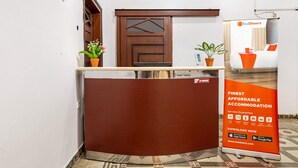 Un comptoir d’accueil avec une porte en bois, des plantes en pot et une publicité pour RedDoorz.