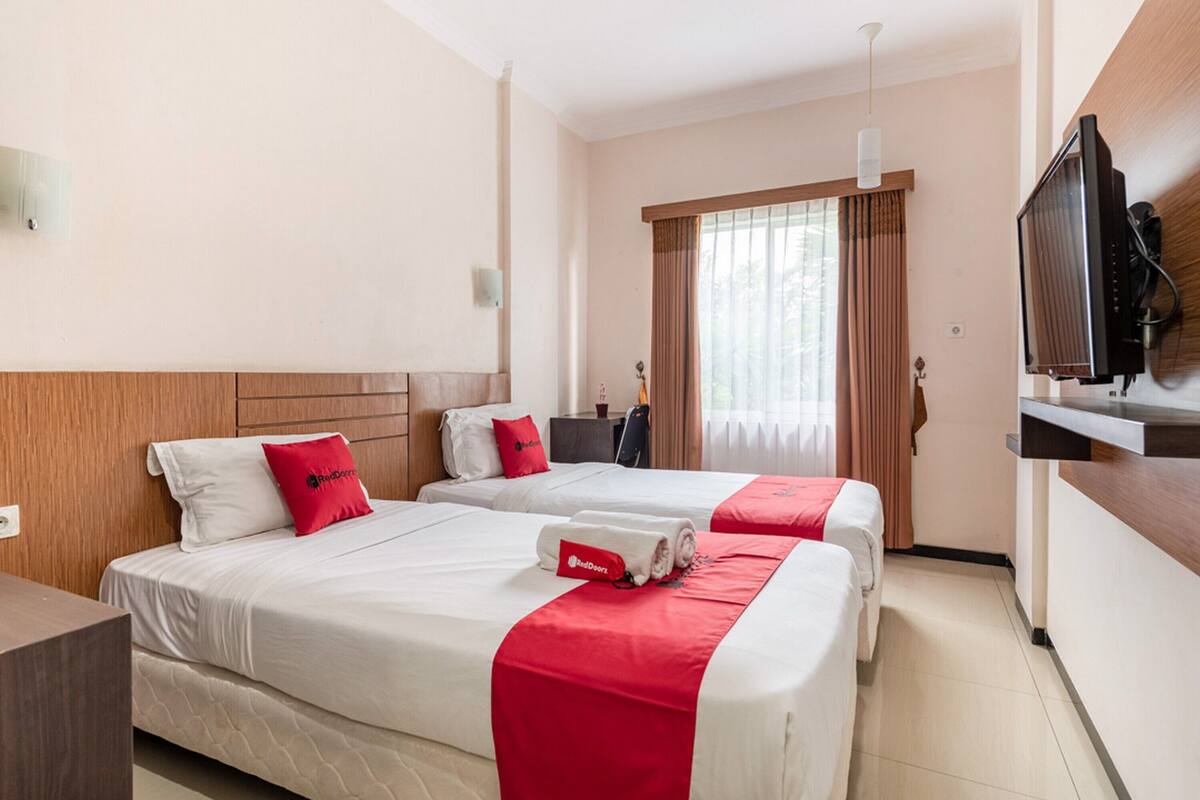 Habitación de hotel con dos camas, televisión y escritorio.