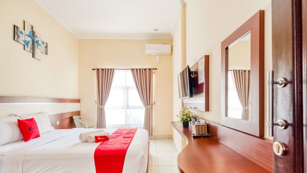 Een hotelkamer met een bed, een televisie, een bureau en een spiegel in de badkamer.