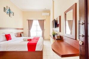 Una camera d'albergo con un letto, una televisione, una scrivania e uno specchio nel bagno.