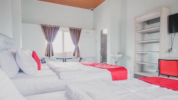 A hotel room with two beds, a desk, a chair, a TV, and a bathroom. - RedDoorz @ Jalan Pangeran Antasari Lampung 2 (Bandar Lampung)