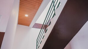 A modern staircase with a wooden ceiling and green railings. - RedDoorz @ Jalan Pangeran Antasari Lampung 2 (Bandar Lampung)