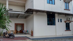 A two-story building with a covered outdoor area, a scooter parked in front, and a potted plant. - RedDoorz @ Hotel Bumi Palupy (Palu)