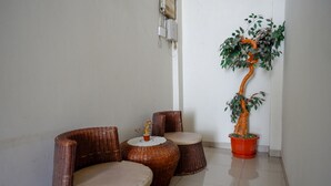 A corner of a room with wicker furniture, a potted plant, and a wall-mounted electrical outlet. - RedDoorz @ Hotel Bumi Palupy (Palu)