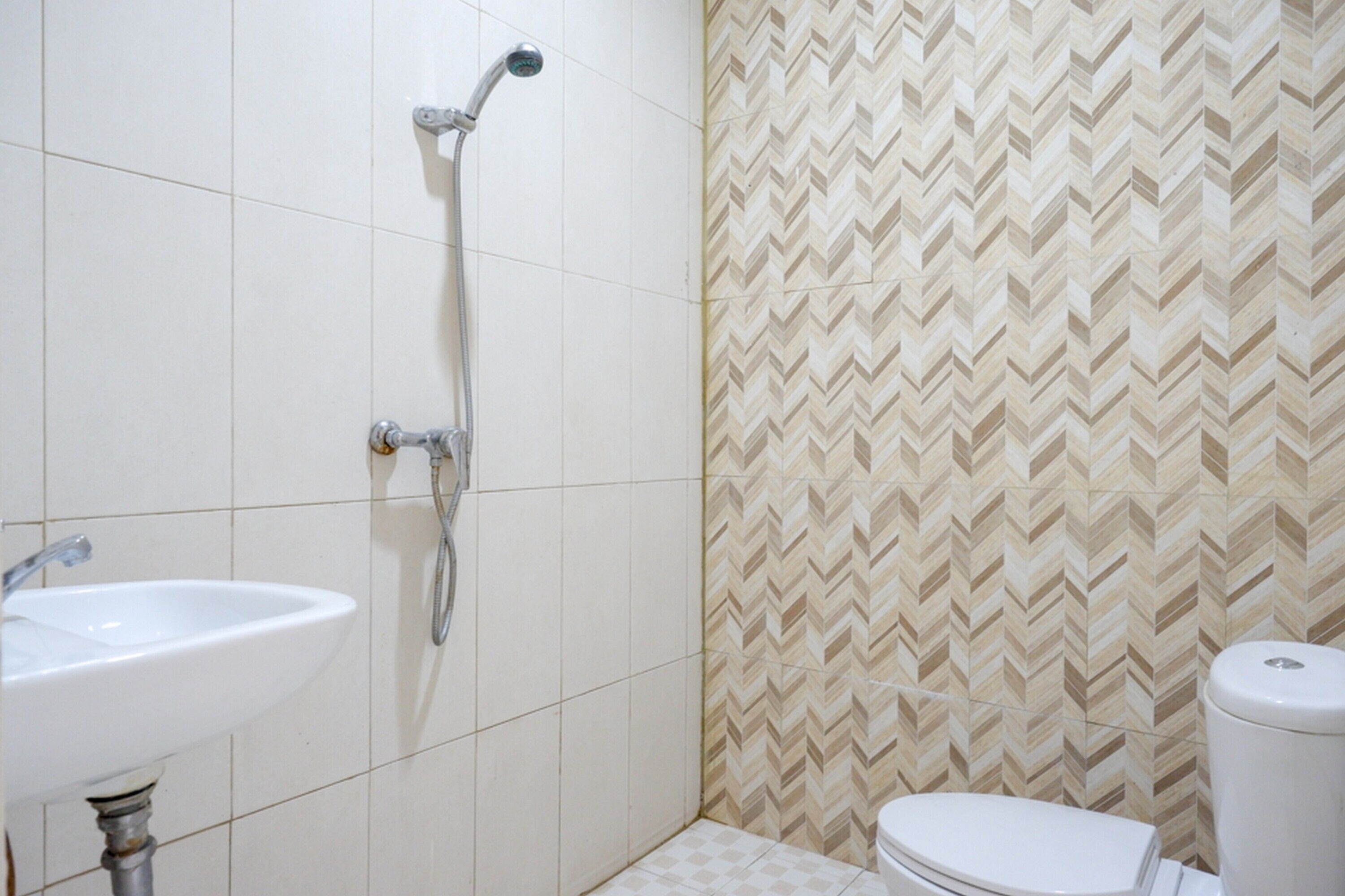 A bathroom with a white sink, a shower, and a toilet. The walls have a chevron pattern.