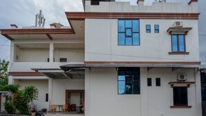 A two-story residential building with a flat roof, large windows, and a visible air conditioning unit. - RedDoorz @ Hotel Bumi Palupy (Palu)