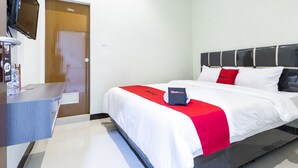 A hotel room with a bed, a desk, a television, and an air conditioning unit. - RedDoorz near Medan Amplas (Medan)
