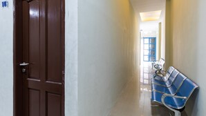 A hallway with a brown door, a blue bench, and a number '103' on the wall. - RedDoorz near Medan Amplas (Medan)