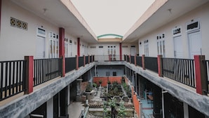 A multi-level courtyard with a central open area surrounded by buildings with balconies and railings. - RedDoorz Syariah near Kebun Raya Liwa (Gunung Sugih)