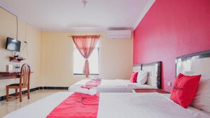 A hotel room with two beds, a TV, a desk, and a chair. - RedDoorz Syariah near Kebun Raya Liwa (Gunung Sugih)