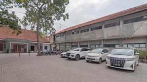 A parking area with several white SUVs, a building with a tiled roof, and string lights. - RedDoorz near Alun-Alun Garut (Garut)