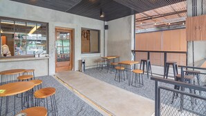 An interior with tables and chairs, a concrete floor, and a metal ceiling. - RedDoorz near Alun-Alun Garut (Garut)