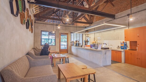 A modern interior with a high ceiling, exposed beams, and a seating area with a sofa and tables. - RedDoorz near Alun-Alun Garut (Garut)
