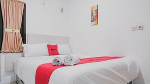 A hotel room with a bed, a red throw blanket, a white pillow, and a red pillow. - RedDoorz near Jalan Soeprapto Bengkulu (Bengkulu)