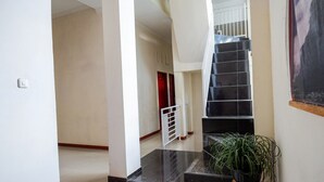 Un escalier avec une rampe, un pot de fleurs et une porte en arrière-plan.