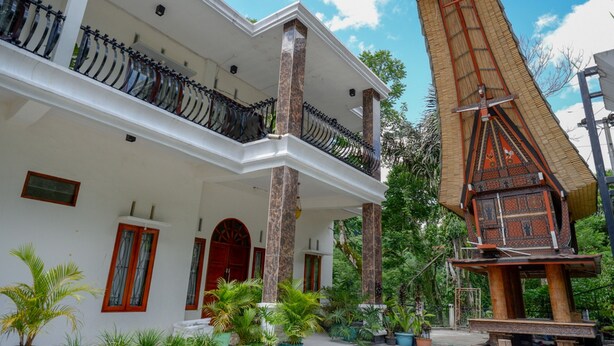 Un bâtiment à deux étages doté d’un balcon, d’une structure traditionnelle en bois et de plantes en pot.