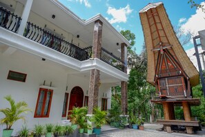 Ein zweistöckiges Gebäude mit Balkon, eine traditionelle Holzkonstruktion und Kübelpflanzen.